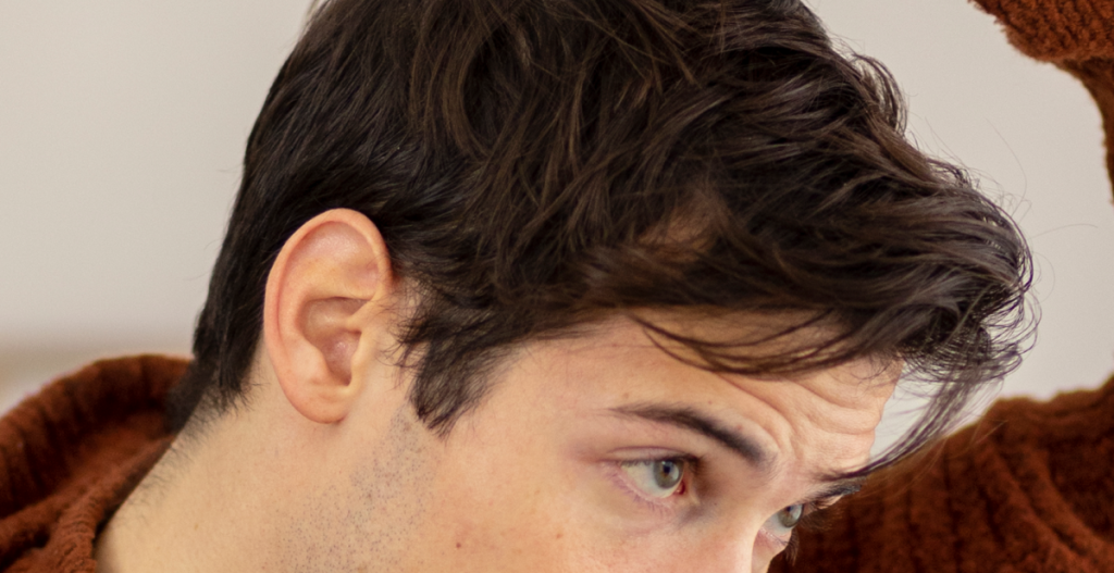 Hombre acomodando su cabello con las manos, rutina de cuidado del cabello en invierno para mantener fuerza y densidad.