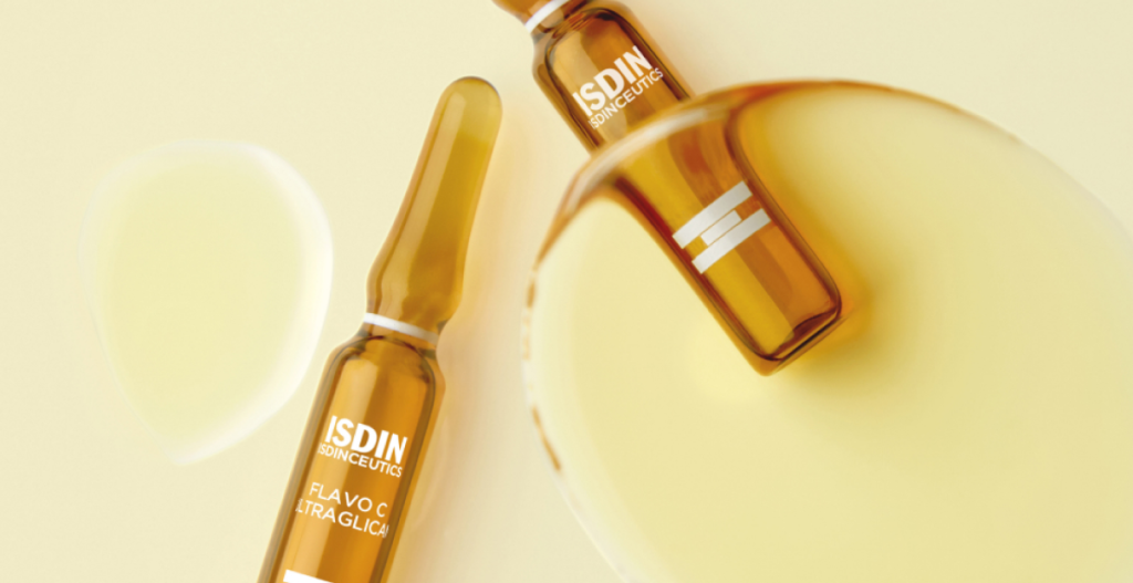 Primer plano de ampollas ISDIN Isdinceutics Flavo-C Ultraglicanos sobre fondo blanco, producto cosmético en formato sérum para el cuidado de la piel.