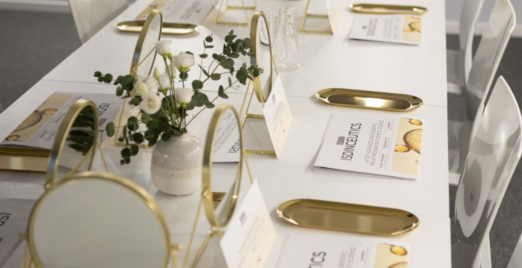 Mesa preparada para un encuentro en Casa ISDIN con espejos, flores y materiales informativos sobre bienestar.