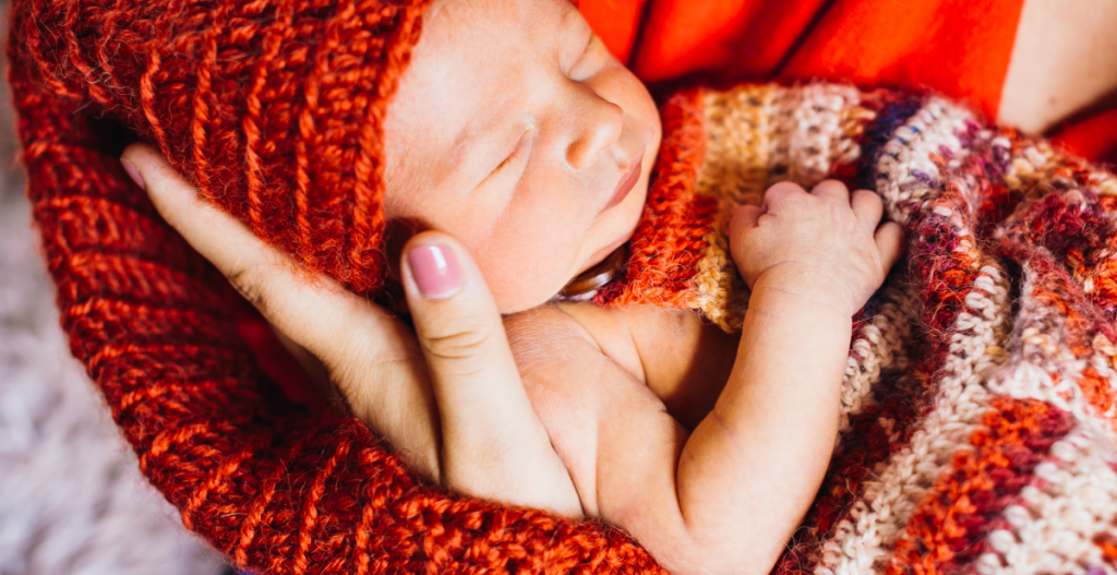 Recién nacido envuelto en manta de lana, mostrando la sensibilidad de su piel.