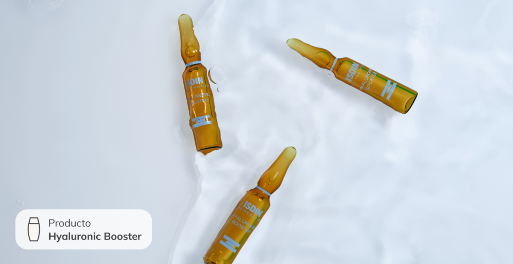 Ampollas de vidrio ámbar flotando sobre agua con reflejos suaves. Producto ISDIN Hyaluronic Booster, sérum concentrado para aplicar en el rostro y preparar la piel antes de celebraciones