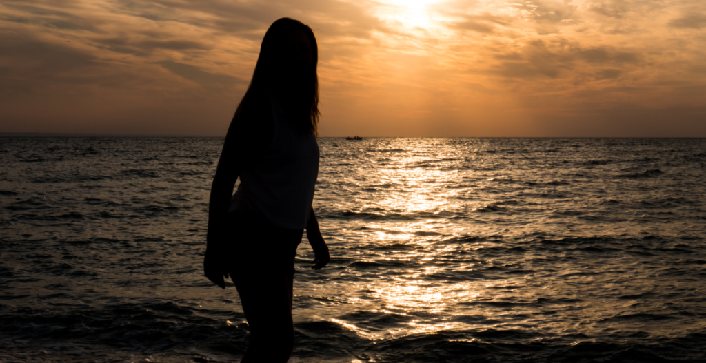 Persona caminando junto al mar al atardecer durante una escapada de fin de semana