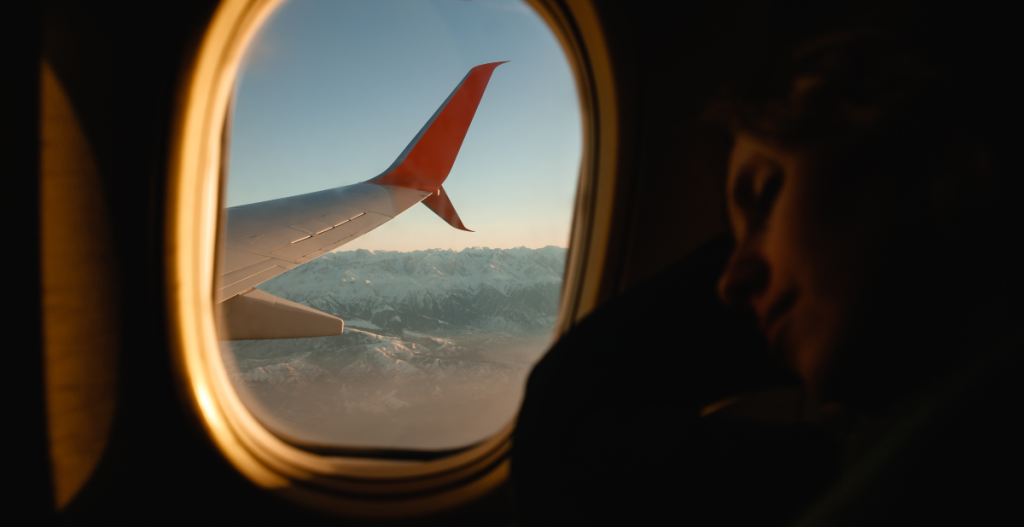 Vista desde la ventana de un avión con paisaje de montañas al fondo durante un viaje