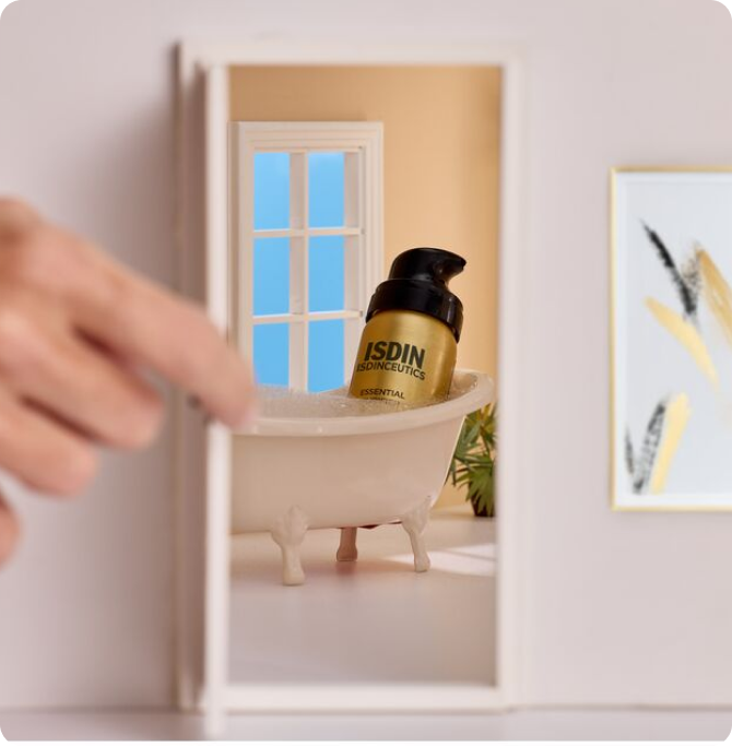 Producto limpiador facial ISDIN en formato mini colocado en una bañera en miniatura