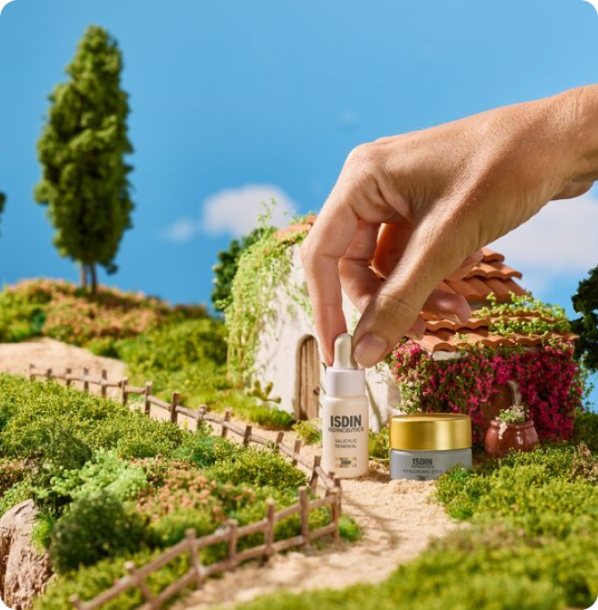 Sérum facial ISDIN en formato mini sostenido sobre maqueta de paisaje natural