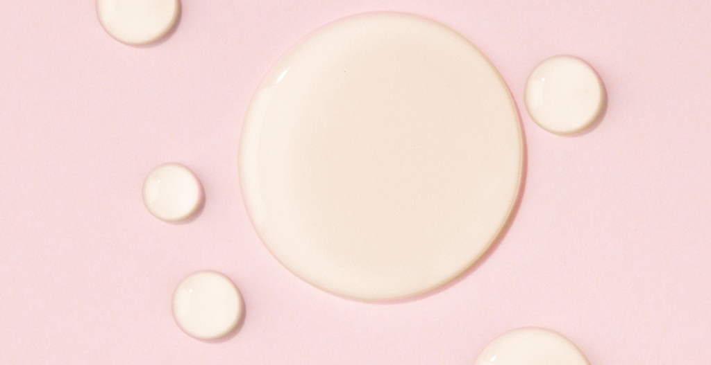 Textura de producto hidratante sobre fondo rosa que representa soluciones para la sequedad vaginal y el confort íntimo.