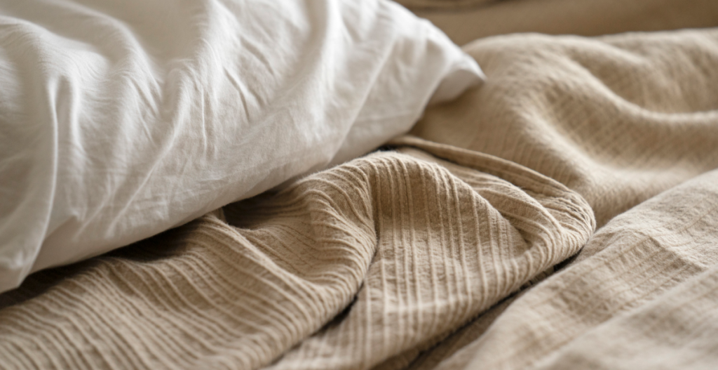 Sábanas suaves sobre una cama que evocan descanso nocturno y bienestar