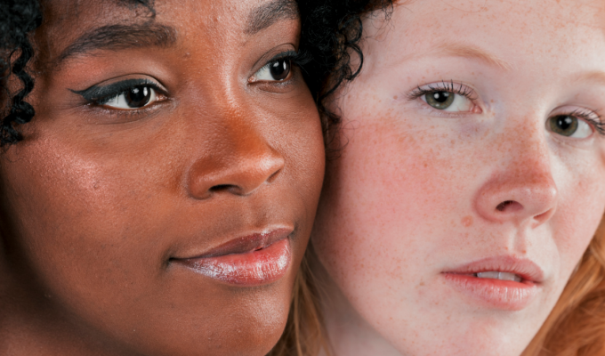 Primer plano de dos mujeres con diferentes tonos de piel mostrando naturalidad y luminosidad, ejemplo de cómo ingredientes antimanchas como niacinamida, ácido tranexámico y vitamina C funcionan en todo tipo de piel.