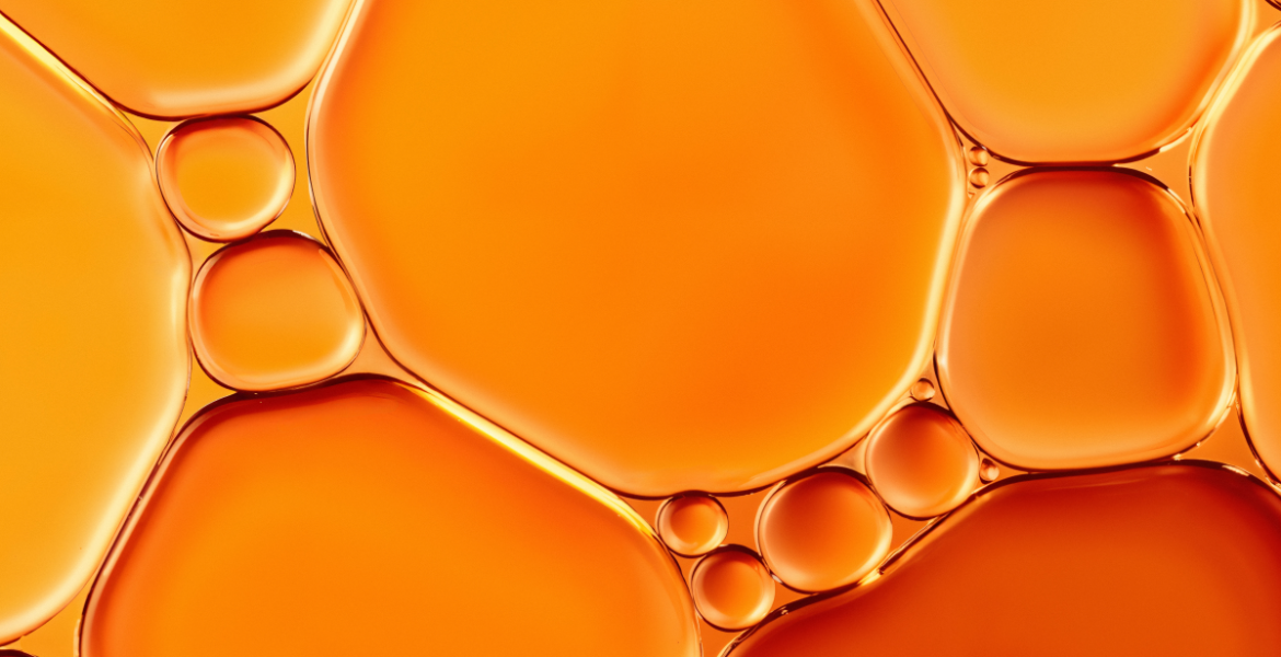 Textura líquida en tonos naranjas que representa la vitamina C y su acción antioxidante en la piel