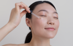 Mujer aplicando sérum facial con gotero en la mejilla, parte de la rutina de skin cycling para hidratar y regenerar la piel