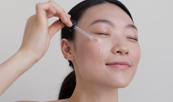 Mujer aplicando sérum facial con gotero en la mejilla, parte de la rutina de skin cycling para hidratar y regenerar la piel