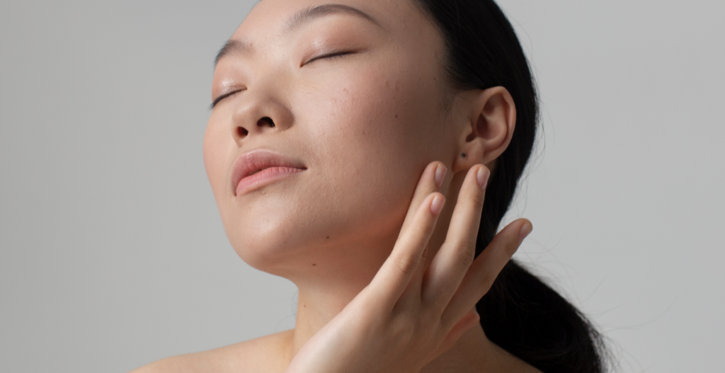 Mujer acariciando su rostro con expresión relajada tras aplicar crema facial en su rutina