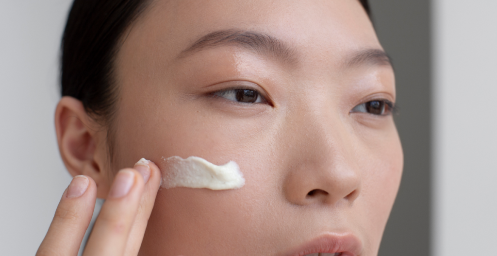 Primer plano de una mujer aplicando crema hidratante en la mejilla, paso esencial dentro del skin cycling