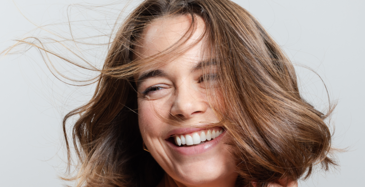 Mujer sonriente con cabello corto, brillante y con movimiento, símbolo de un cabello fuerte y sin signos de caída.