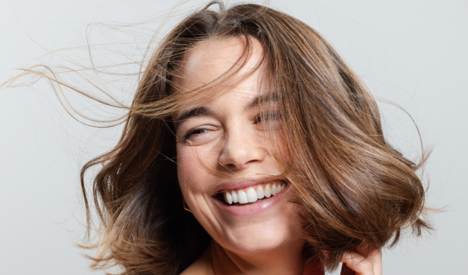 Mujer sonriente con cabello corto, brillante y con movimiento, símbolo de un cabello fuerte y sin signos de caída.