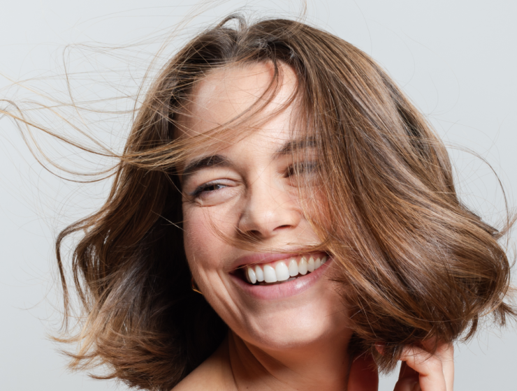 Mujer sonriente con cabello corto, brillante y con movimiento, símbolo de un cabello fuerte y sin signos de caída.