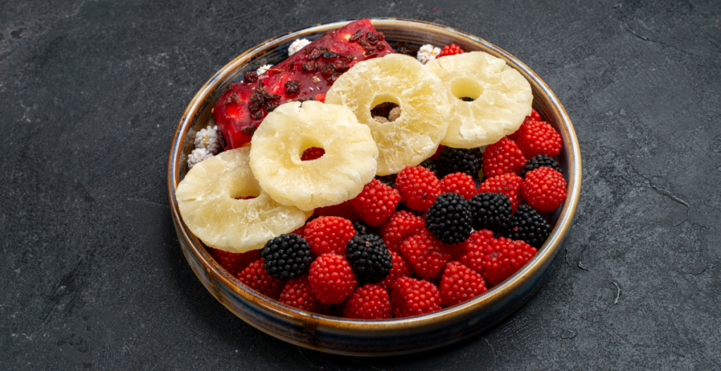 Plato con rodajas de piña, frambuesas y moras, alimentos ricos en nutrientes que apoyan la salud capilar.