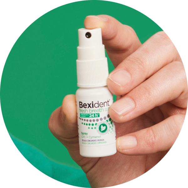 Mano sosteniendo Bexident Fresh Breath spray bucal, formato práctico para refrescar el aliento fuera de casa.