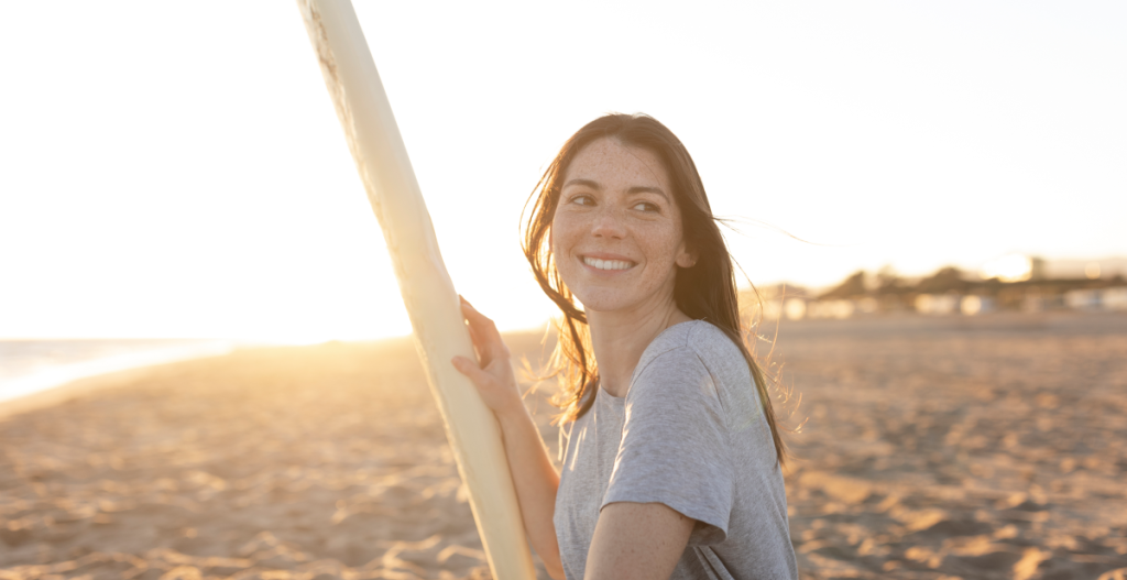 chica sonriendo en la playa mientras el sol refleja en su rostro