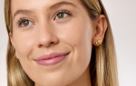 Primer plano de mujer joven de piel clara con acabado natural en la piel y pequeñas imperfecciones visibles en la mejilla.