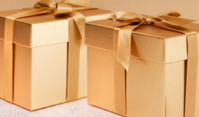 Cajas de regalo doradas con lazo sobre fondo claro, representando ideas de regalo de Navidad elegantes y sofisticadas