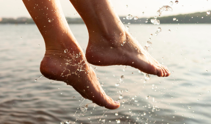 Pies descalzos saliendo del agua con gotas visibles, imagen que representa hidratación natural y cuidado de pies secos y talones agrietados