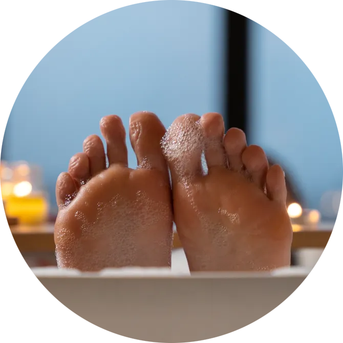 Plantas de los pies durante un baño relajante con espuma, rutina de cuidado para pies secos y prevención de talones agrietados