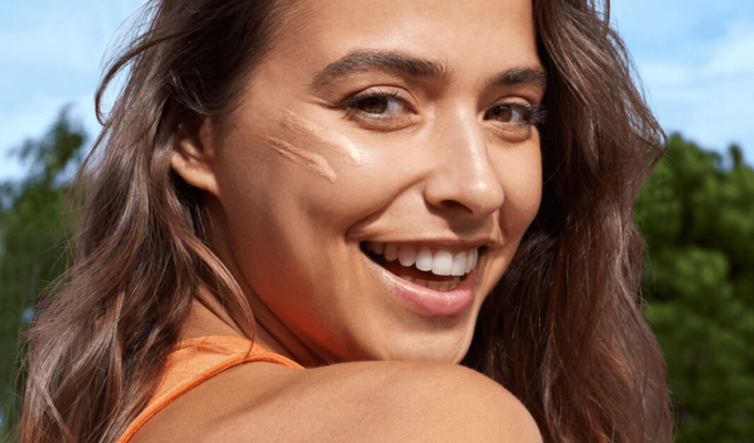 Primer plano de mujer con crema facial en la mejilla, rutina de protección solar para una piel radiante