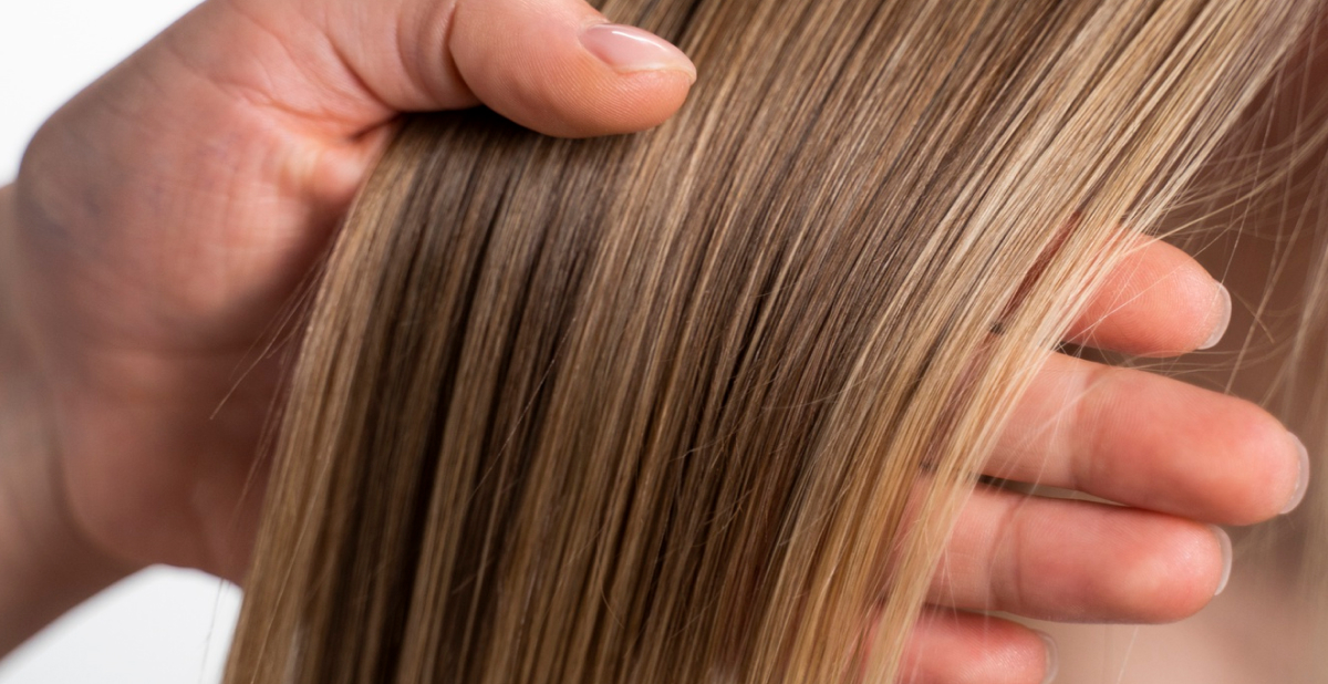 Primer plano de una persona examinando el estado y la densidad de varios mechones de cabello