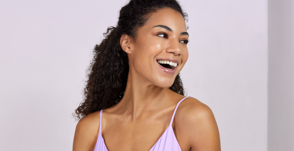 Mujer sonriendo con piel luminosa y aspecto saludable, representando bienestar y cuidado facial capas de la piel