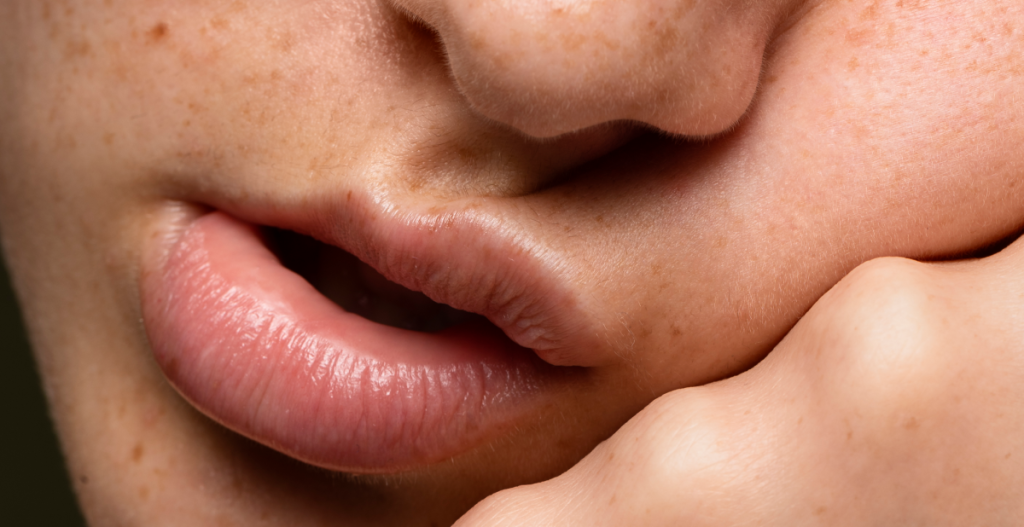 Primer plano de labios y piel con pecas que muestra textura natural y luminosidad cutánea