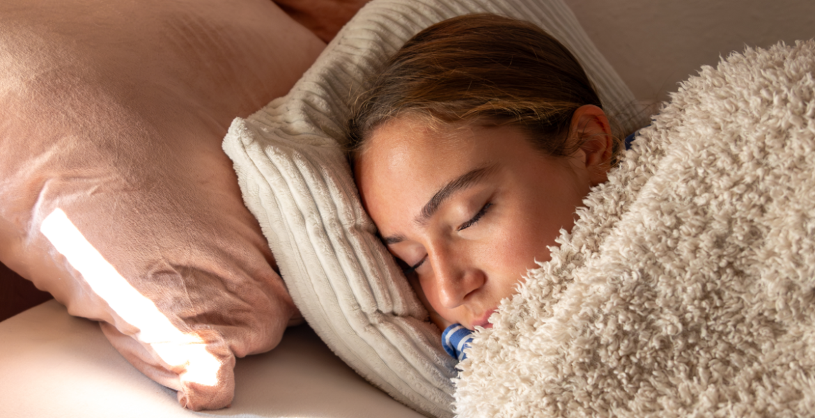 Persona durmiendo cómodamente bajo una manta suave, ejemplo de descanso profundo durante la noche.