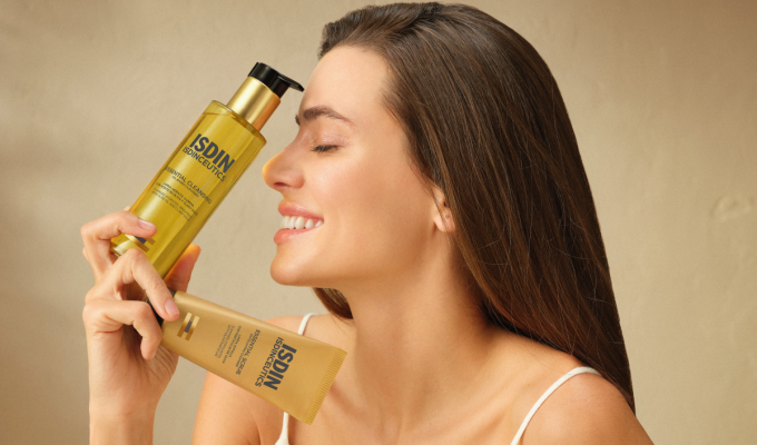 Mujer sosteniendo limpiadores de rostro isdin para el día a día, cosméticos de calidad
