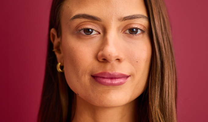 Primer plano de una mujer con maquillaje natural y labios en tono rosa, mostrando un look fresco y protegido del sol.