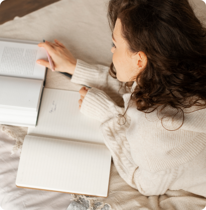 Mujer leyendo un libro y escribiendo en un cuaderno sobre la cama, creando una rutina relajante antes de dormir para mejorar la calidad del sueño.