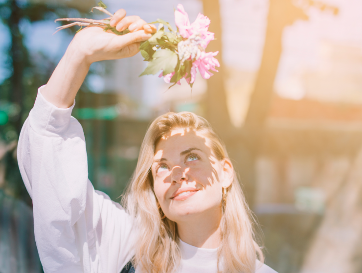 chica sonriendo con flores tras hacerse rutina facial diaria de mañana