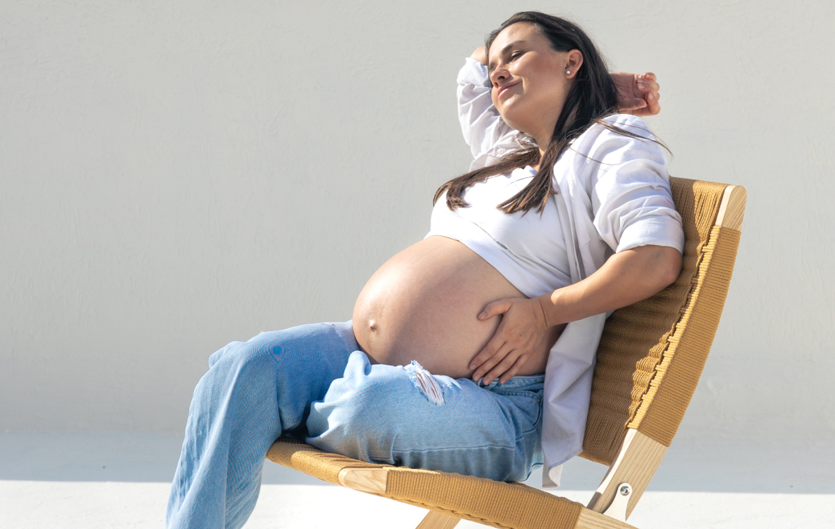 Mujer embarazada tomando el sol sentada en una silla durante el verano