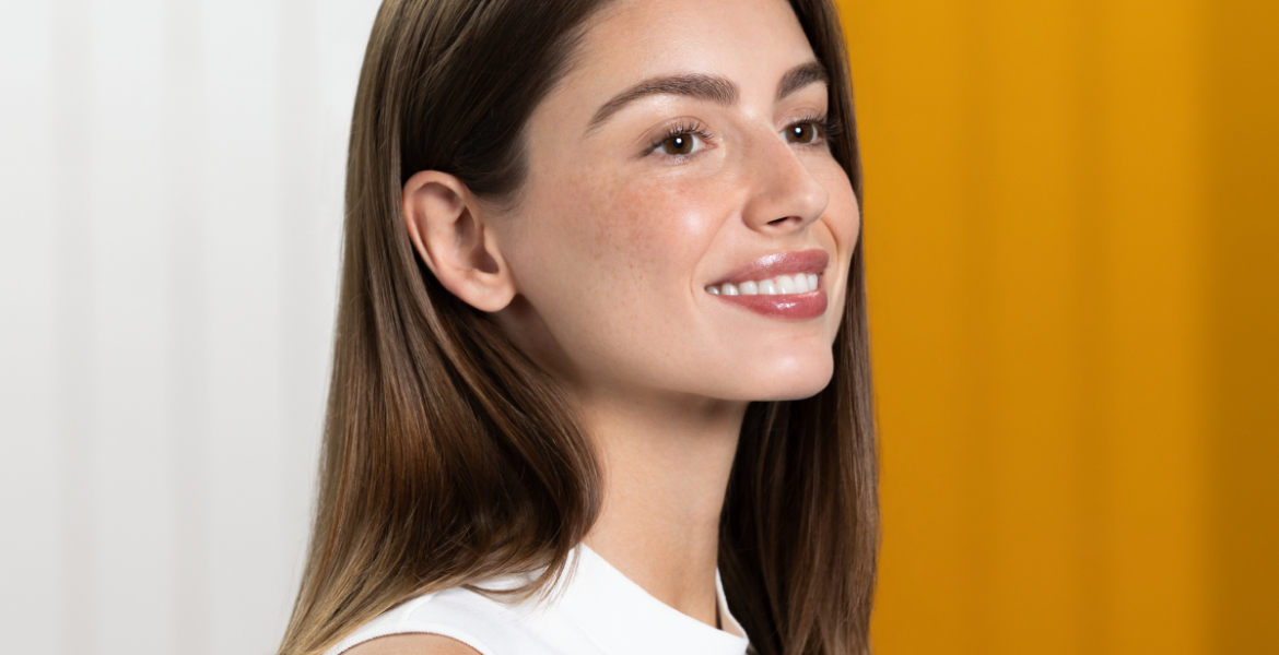 Mujer sonriente con piel uniforme y luminosa, resultado de una rutina de cuidado con productos despigmentantes ISDIN