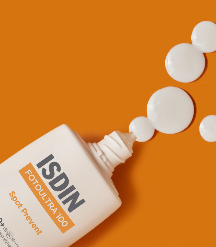Envase de ISDIN FotoUltra 100 Spot Prevent con textura fluida blanca, diseñado para prevenir manchas solares y proteger la piel del fotoenvejecimiento