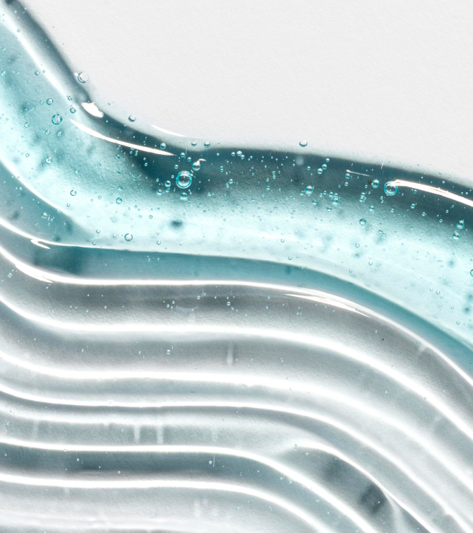 Textura macro de agua con ondas suaves y burbujas sobre fondo claro. Representa frescura, pureza e hidratación como símbolo visual de hábitos saludables.