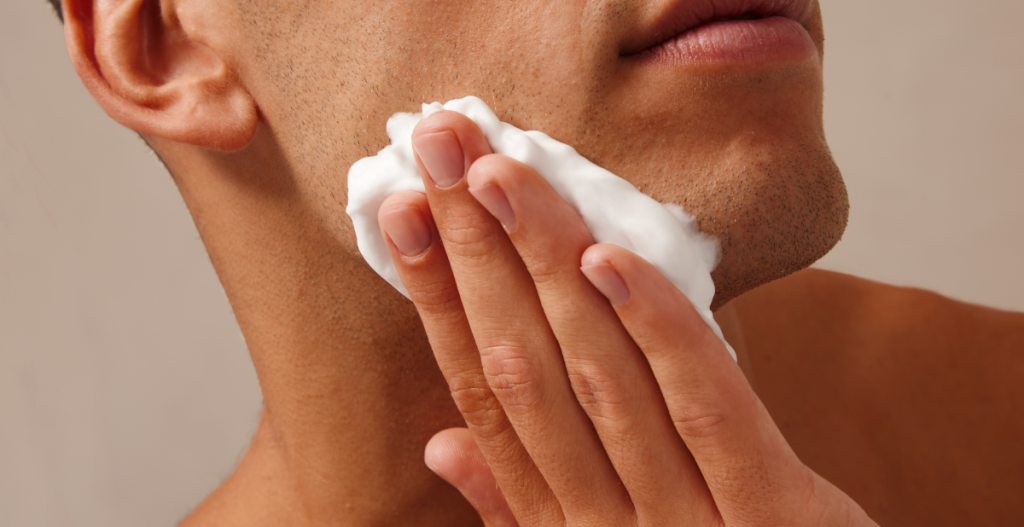 Hombre limpiando su rostro con espuma facial, paso básico en una rutina de skincare para hombres