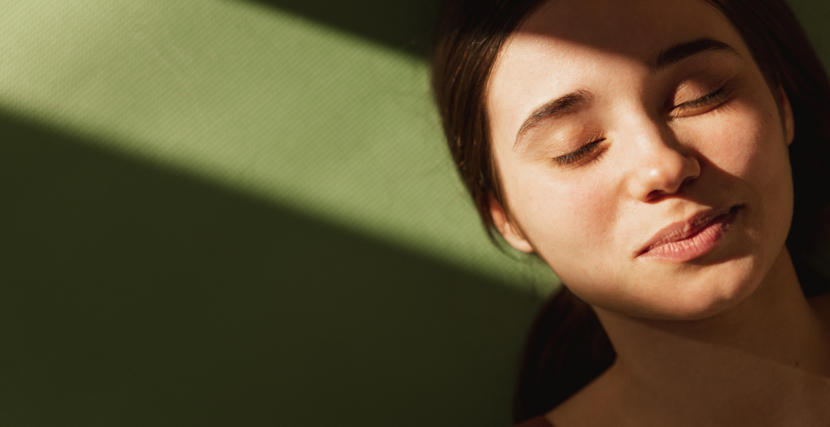 Mujer con los ojos cerrados y el rostro expuesto a la luz solar directa.