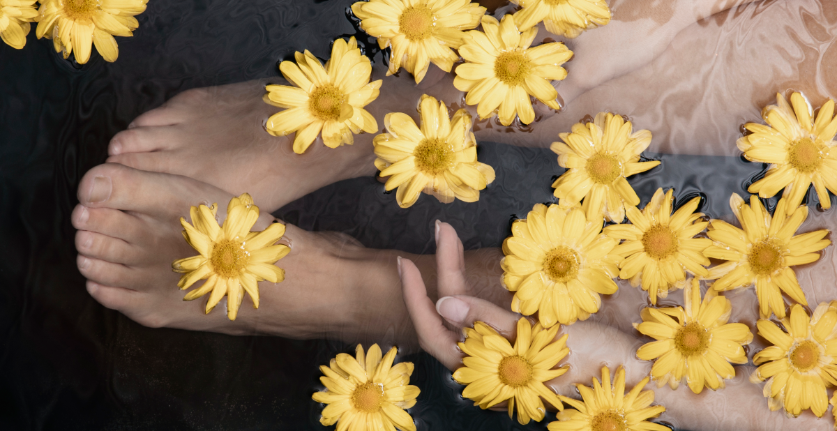 Mujer en bañera con flores amarillas flotando, momento de autocuidado y relajación