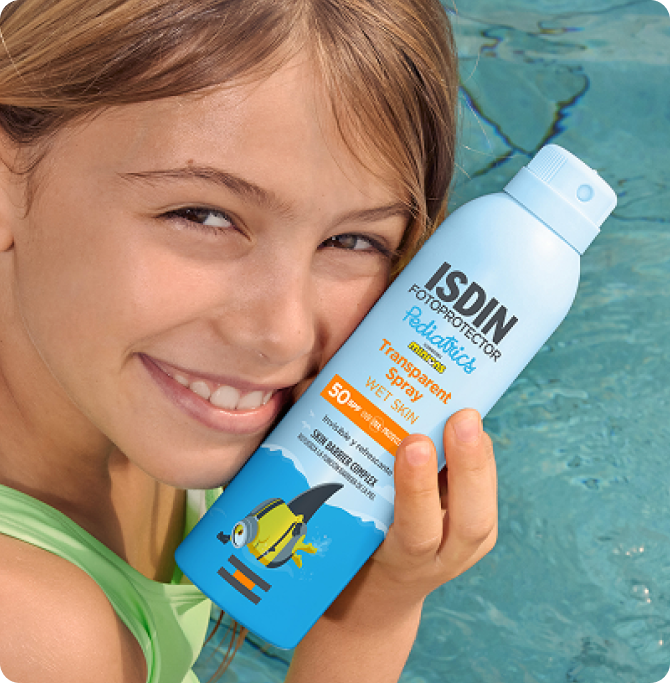 Niña sonriente junto a una piscina sosteniendo el fotoprotector Transparent Spray Wet Skin Pediatrics.