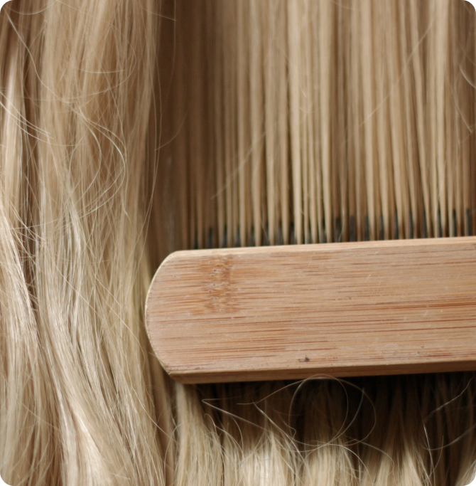 Cepillo de madera entre mechones de cabello rubio.