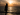 Mujer en silueta frente al mar al atardecer, disfrutando de un momento de calma tras un día de playa