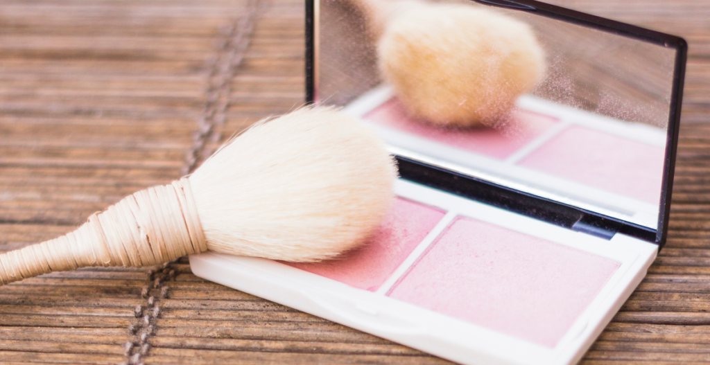 Brocha de maquillaje sobre paleta rosa, recordando la importancia de limpiarlas