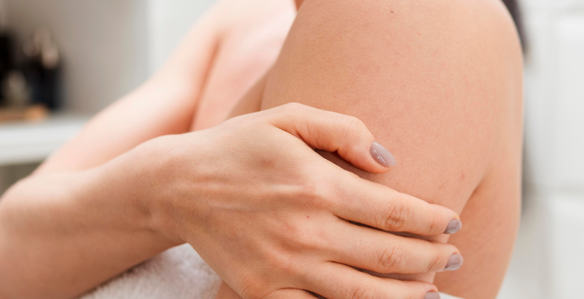 Plano detalle de una mujer tocándose la parte trasera del brazo tras la ducha.