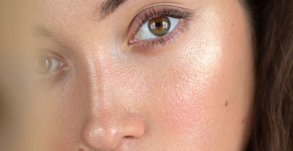 Close-up de piel con textura real, poros y brillo natural. Enfoque: romper el mito de la piel sin poros en 2026, rutina honesta de Año Nuevo