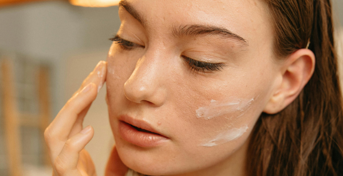 Mujer aplicando crema facial sobre la piel, integrando péptidos en su rutina diaria de skincare ISDIN.